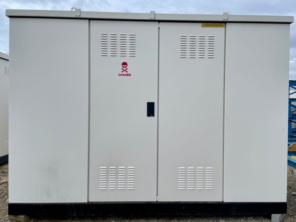 Closed purpose-built metal kiosk of a compact substation with louvred ventilated doors on a black steel base