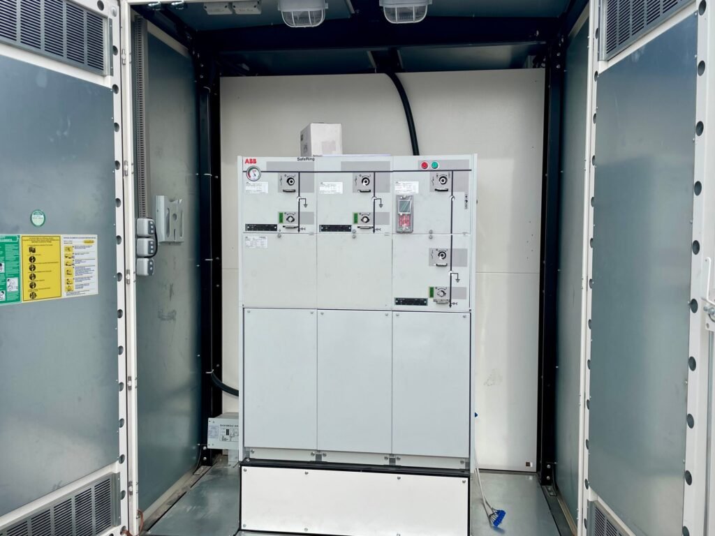 ABB SafeRing ring main unit installed in the medium-voltage compartment of a compact substation metal kiosk, with the compartment doors open